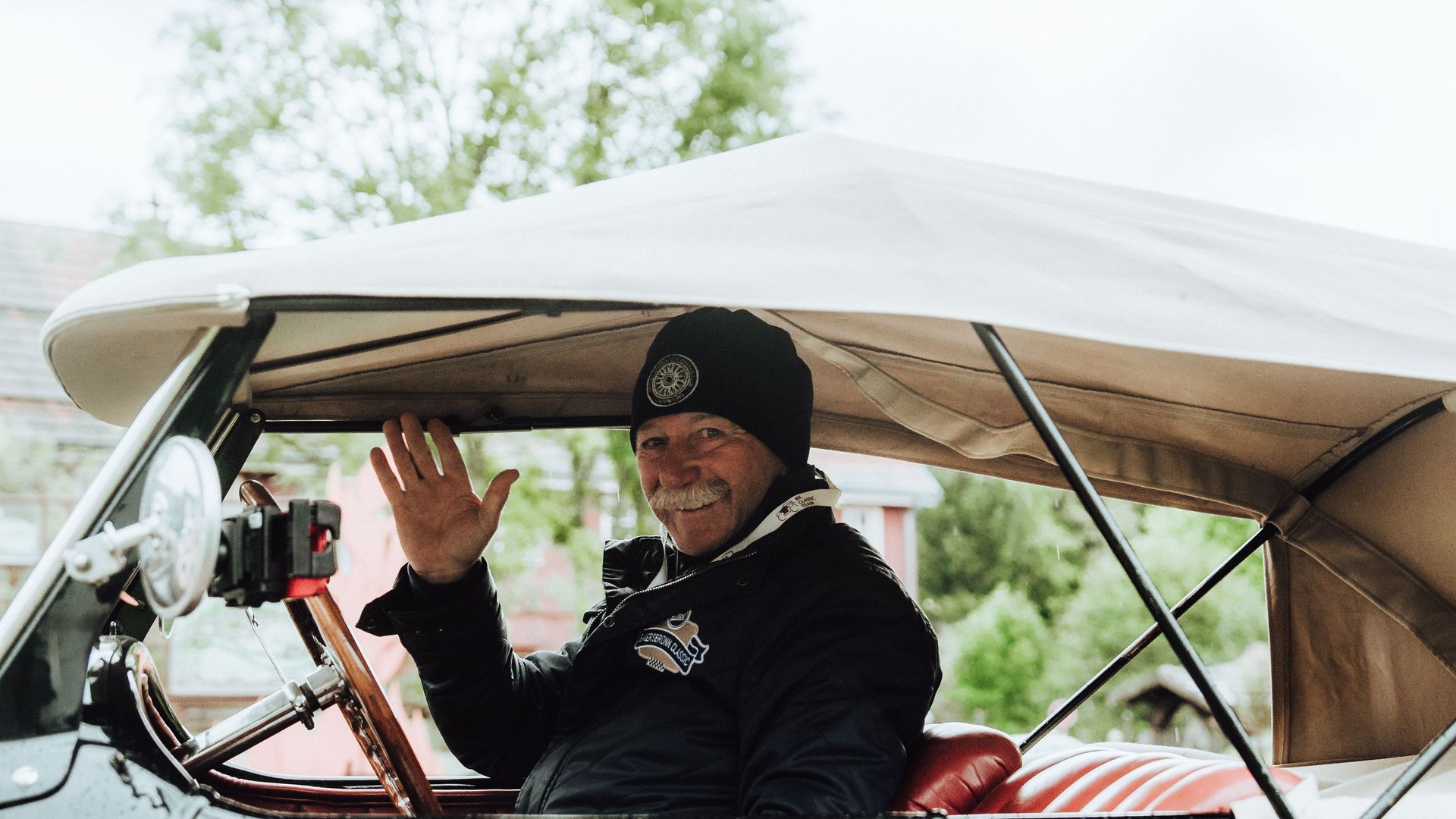 Teilnehmer der Baiersbronn Classic winkt aus seinem Oldtimer