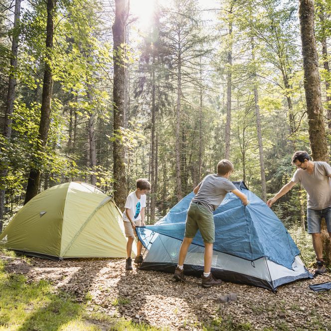Ein Vater baut mit den Kindern die Zelte im Tekking-Camp auf