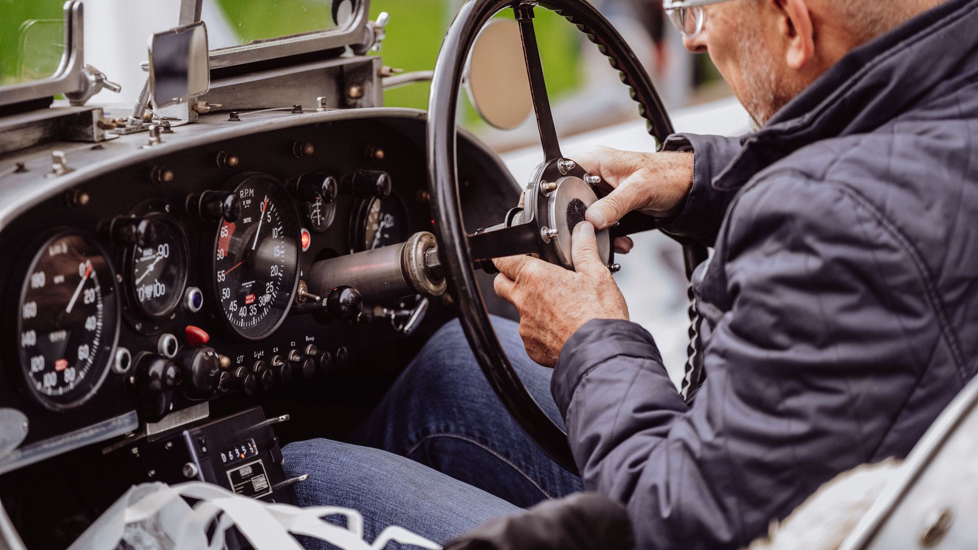 Ein Teilnehmer der Baiersbronn Classic befestigt das Lenkrad in seinem Oldtimer