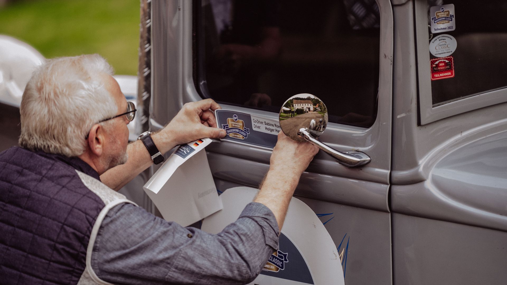 Ein Teilnehmer der Baiersbronn Classic beklebt seinen Oldtimer mit seiner Startnummer