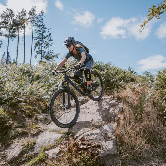 Eine Bikerin fährt über einen felsigen Trail im Baiersbronner Bikehimmel
