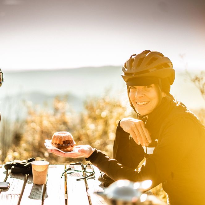 Gravelbiker machen Rast an einer Wanderhütte mit Kaffee und Kuchen