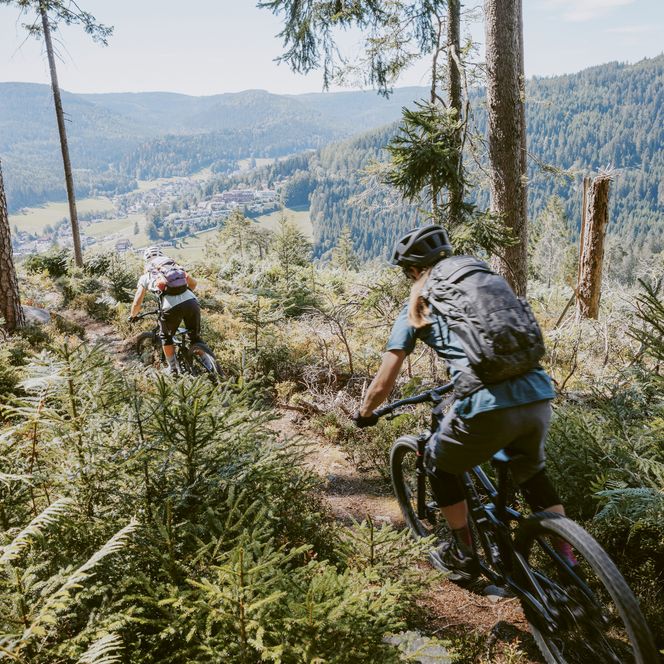 Zwei Frauen fahren auf einem Trail im Baiersbronner Bikehimmel mit einer Aussicht auf Buhlbach