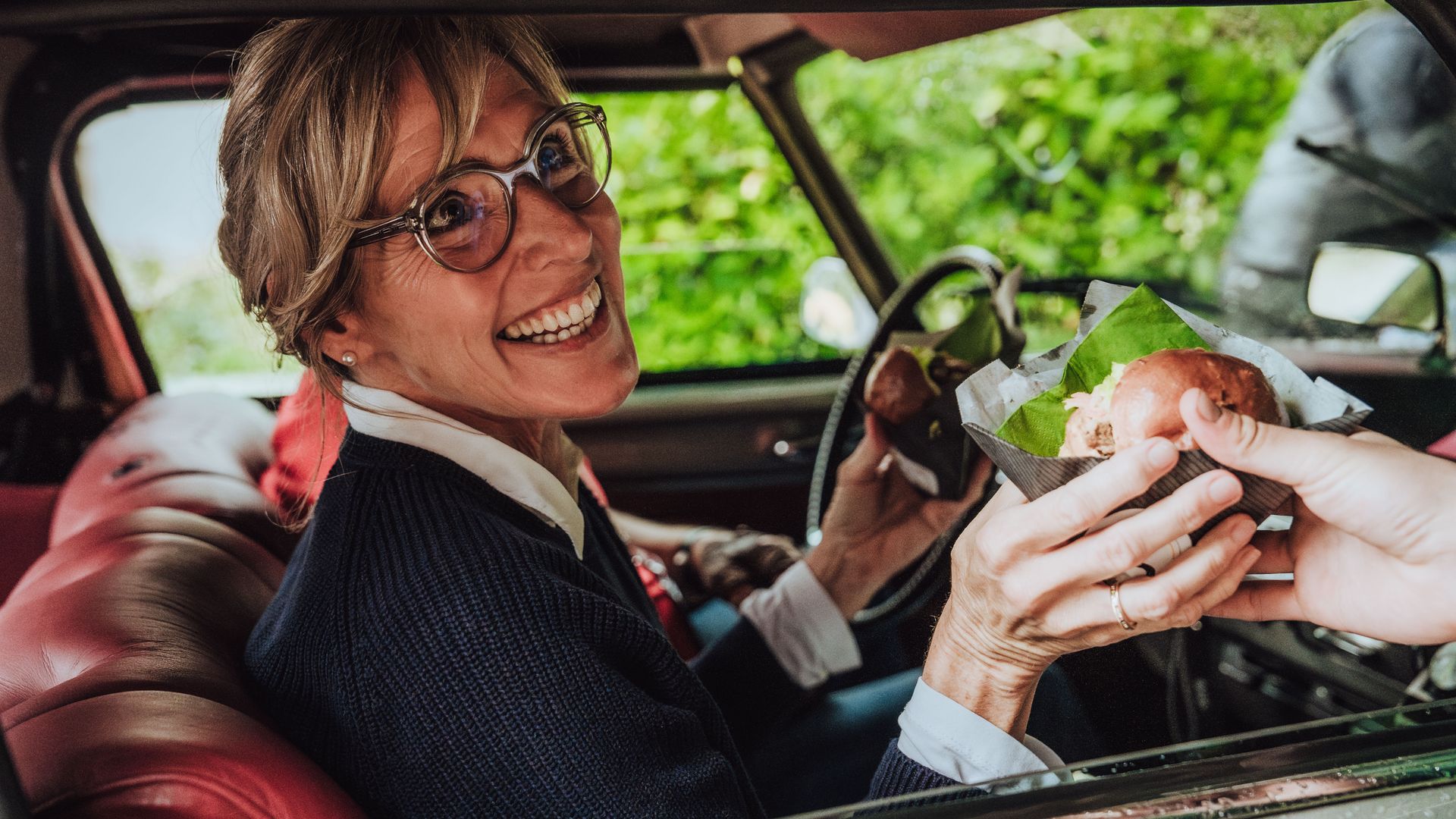 Teilnehmerin der Baiersbronn Classic bekommt Verpflegung in den Oldtimer gereicht