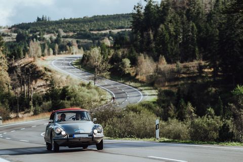Ein dunkelgrüner Oldtimer mit rotem Dach fährt eine Strecke der Baiersbronn Classic bei Sonnenschein