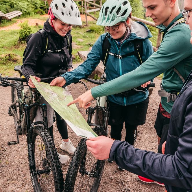 Mountainbikefahrer schauen gemeinsam auf eine Mountainbike Karte