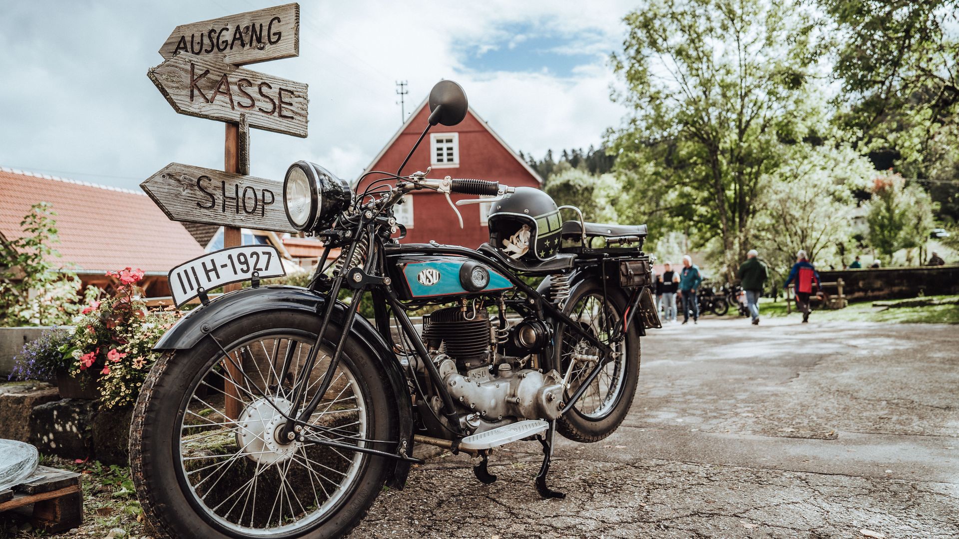 Ein Oldtimer Motorrad der Baiersbronn Classic auf dem Geländer der Glashütte Buhlbach an einem Wegweiser angelehnt