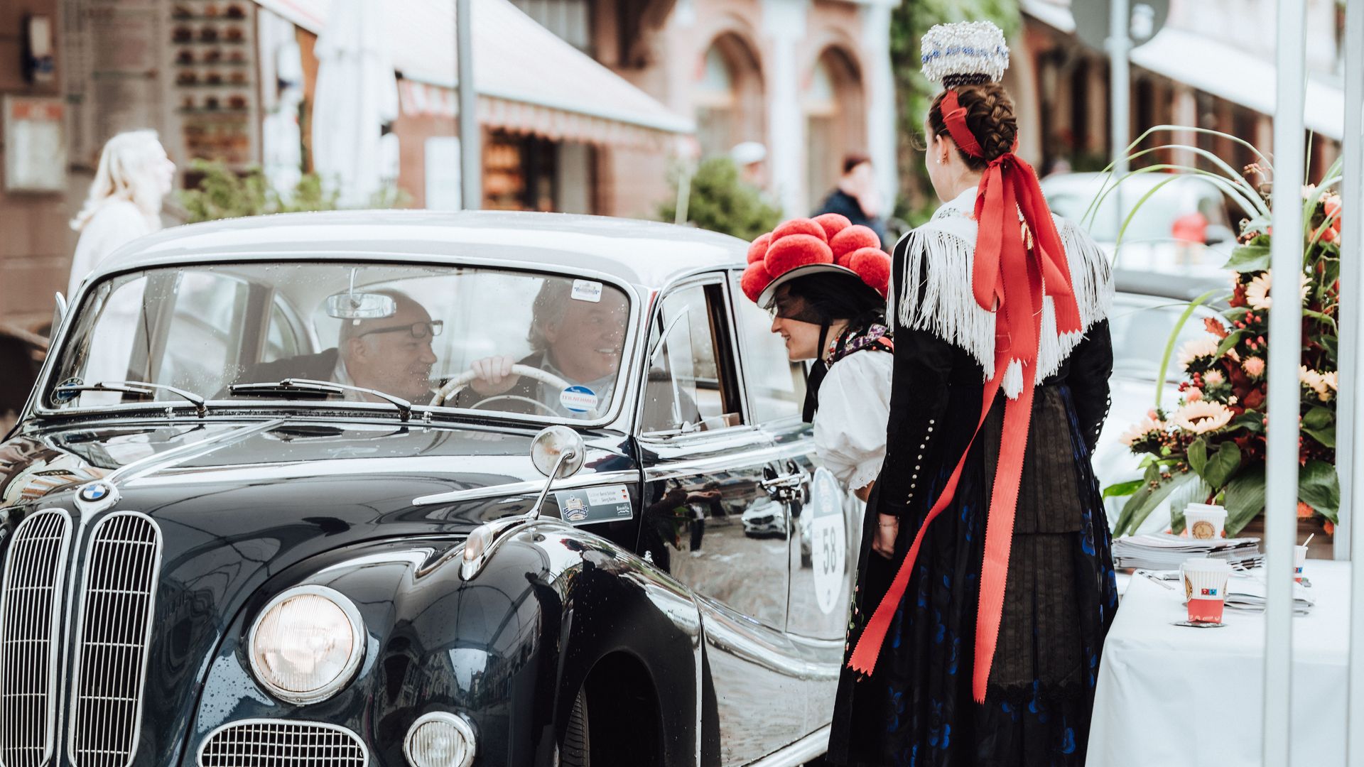 Teilnehmer der Baiersbronn Classic werden von zwei Frauen in Schwarzwälder Kleidung mit Bollenhut begrüßt