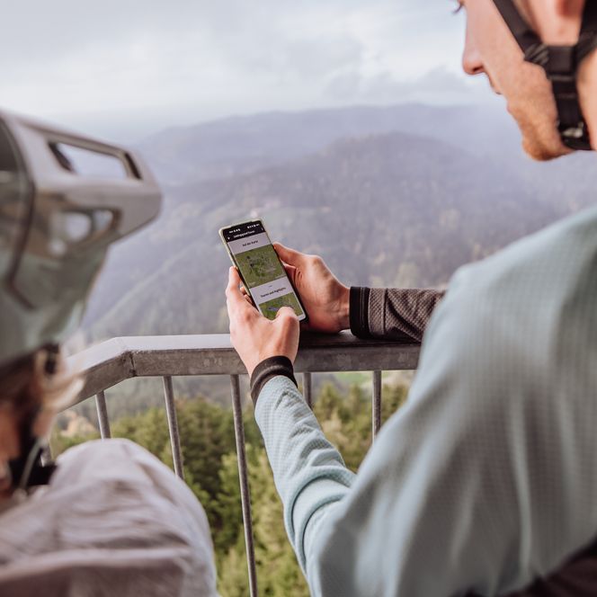 Zwei Gravel-Fahrer schauen auf einem Smartphone nach der Strecke der Gravel-Tour