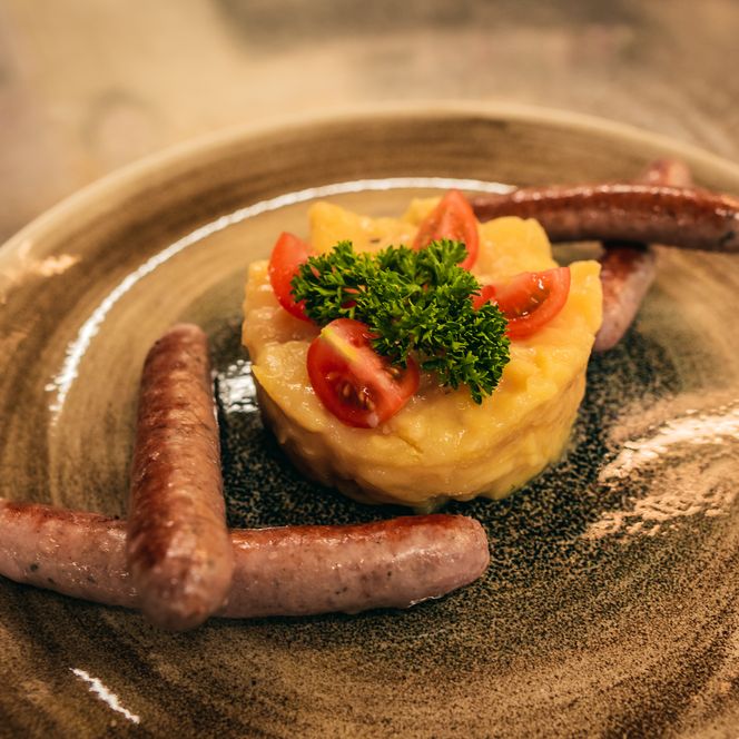 Kartoffelsalat und Würstchen mit Garnitur von Petersilie und Tomaten