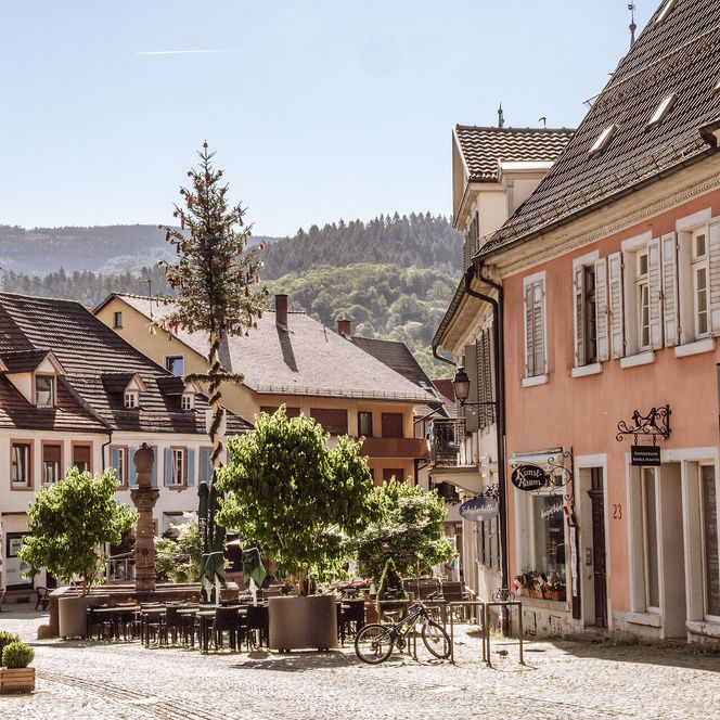 Blick in die Gernsbacher Altstadt mit Brunnen, Brunnen und Bestuhlung von Gastronomie. 