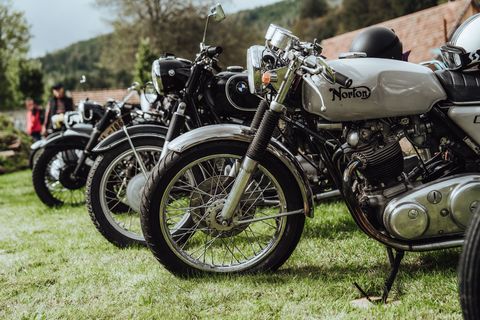 Mehrere Oldtimer Motorräder stehen auf einer Wiese
