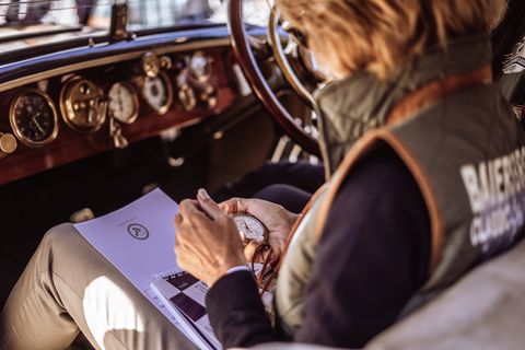 Eine Teilnehmerin der Baiersbronn Classic sitzt in ihrem Oldtimer und misst die Fahrtzeit mit einer Stoppuhr