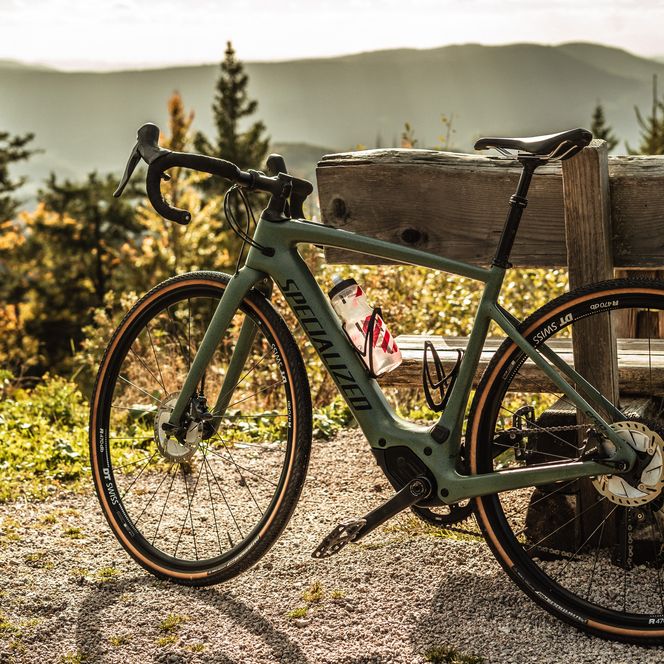 Ein Gravelbike steht angelehnt an einer Holzbank