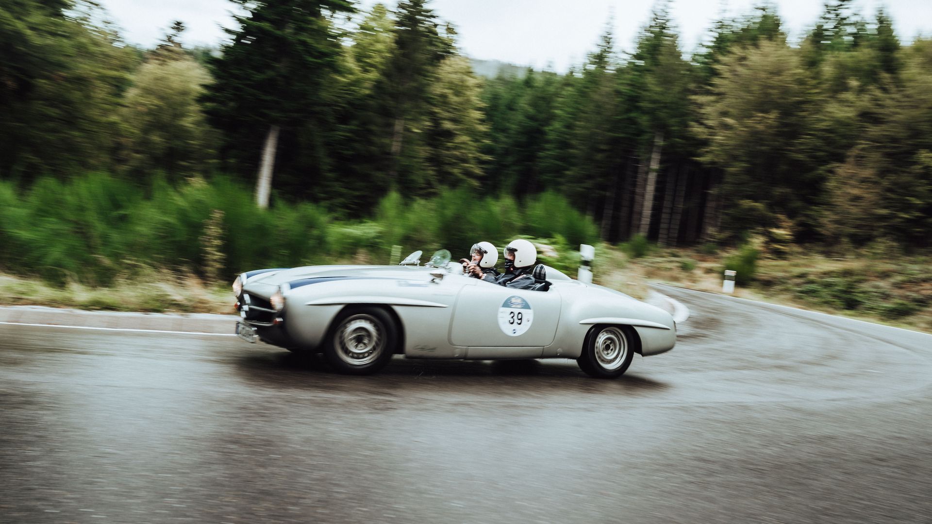 Ein silberner Oldtimer-Cabrio fährt eine Strecke der Baiersbronn Classic im regen