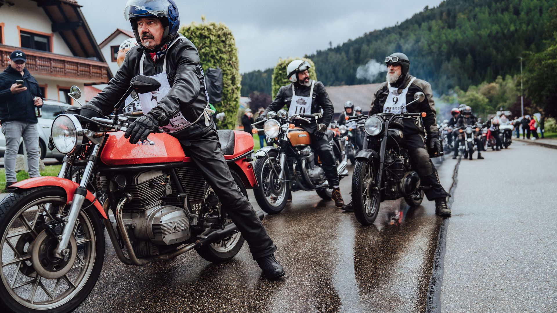 Mehrere Teilnehmer der Baiersbronn Classic warten auf ihren Oldtimer Motorrädern auf den Start des Bergrennens