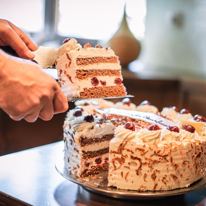 Von einer Schwarzwälder Kirschtorte wird ein Stück angeschnitten